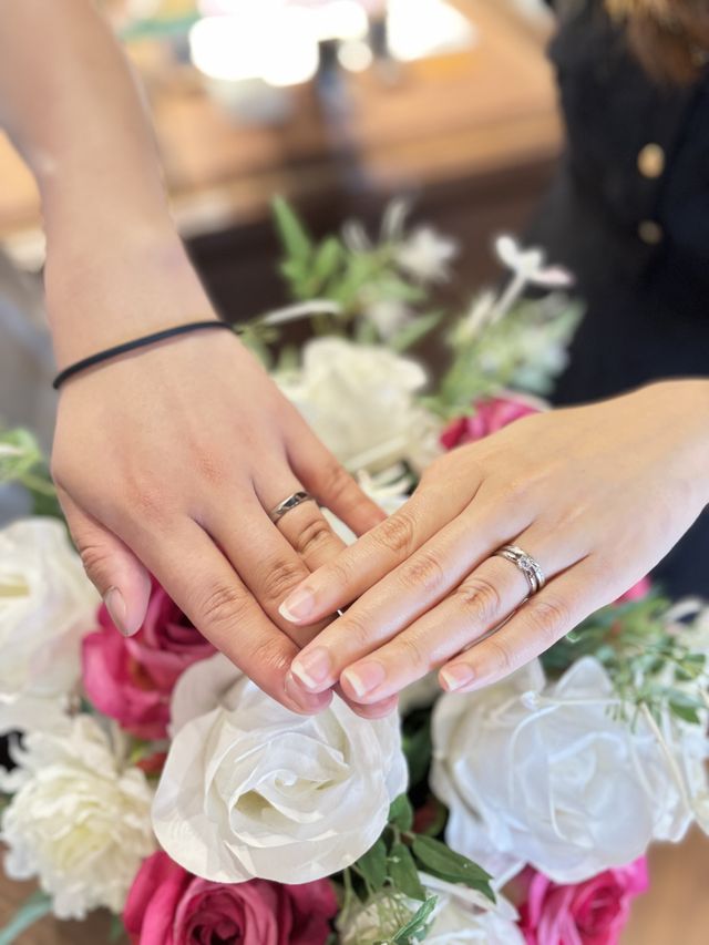 別ブランドの婚約指輪と重ねて結婚指輪を着けている。