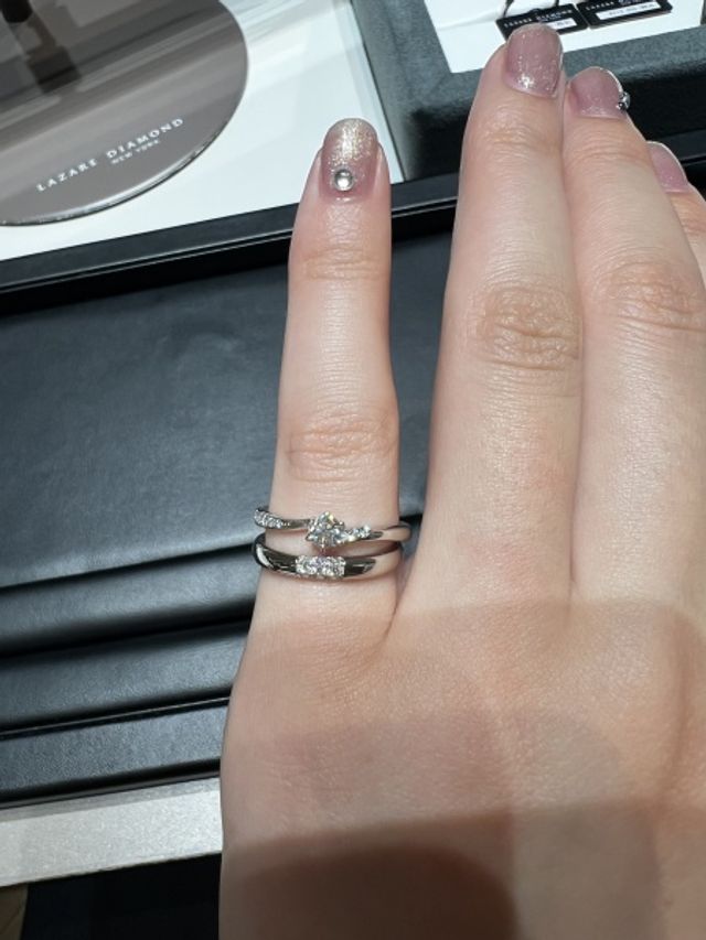 婚約指輪とのペアリングを見ながら試着している様子