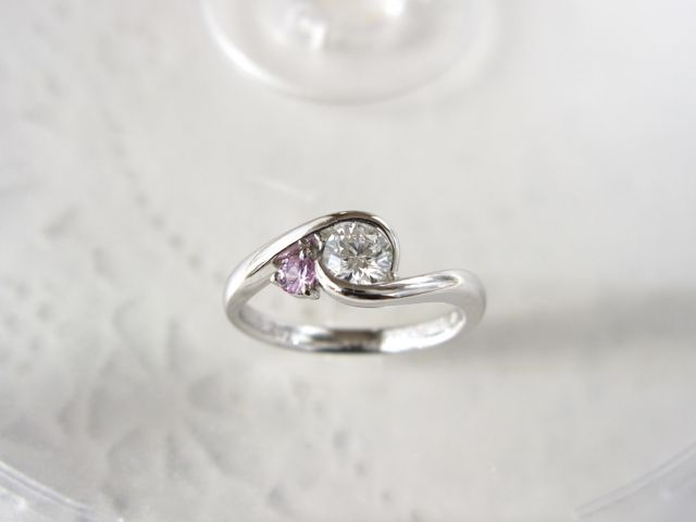 ダイヤを包み込みつつ、横に誕生石を添えるデザインにしました。