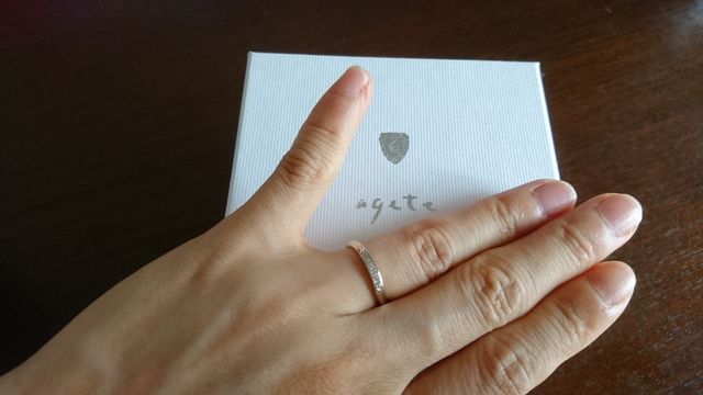 小さなダイヤが5粒施された、少しひねりのある形の結婚指輪